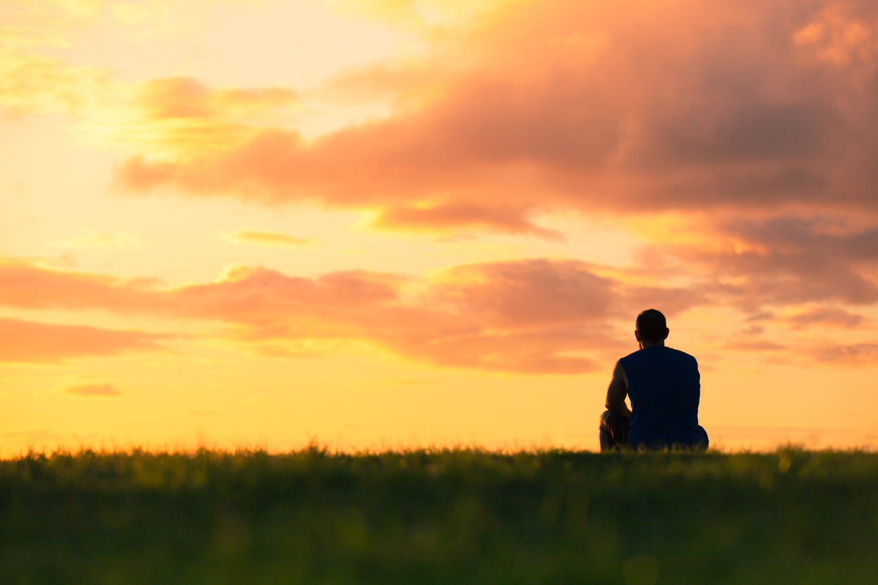 Person sitting alone at peace looking at the dawn.