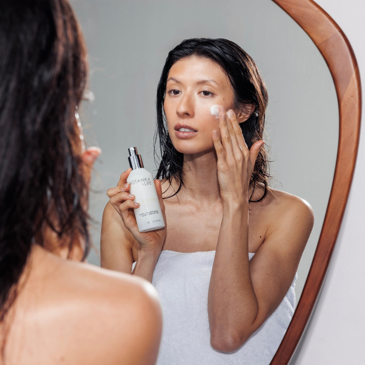 Woman applying Botanika Life facial serum during an at-home luxury skincare routine
